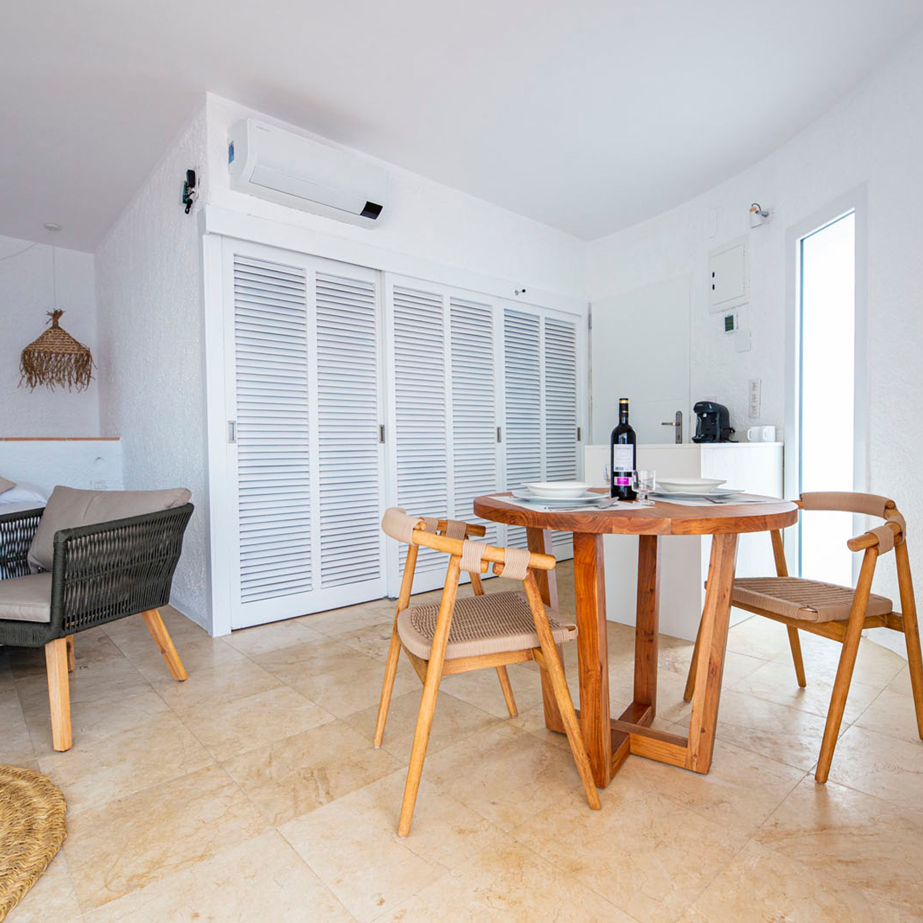 Ein moderner, gut beleuchteter Raum mit einem Essbereich, der einen Holztisch, Stühle, eine Couch und einen Teppich umfasst.