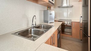 A modern kitchen with stainless steel appliances, a double sink, and wooden cabinets. - Sant Sebastia 111 in Roses (Roses)