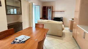 A dining area with a wooden table and chairs, a sofa, and a television in the background. - Sant Sebastia 111 in Roses (Roses)