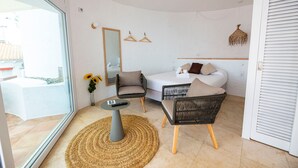 A modern bedroom with a bed, two chairs, a small table, a mirror, and a hanging light fixture. - Castell Mar 1003 in Roses (Roses)