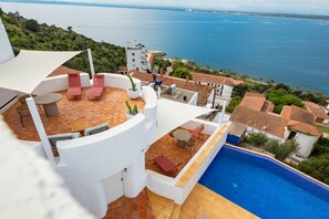 A rooftop terrace with a pool, lounge chairs, and a view of the sea.