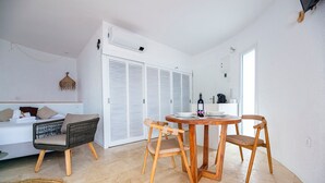 A modern living room with a sofa, two wooden chairs, a round wooden table, and a woven rug. - Castell Mar 1003 in Roses (Roses)