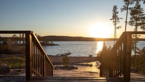 Une terrasse en bois qui mène à un point de vue sur le lac, avec un coucher de soleil en arrière-plan.