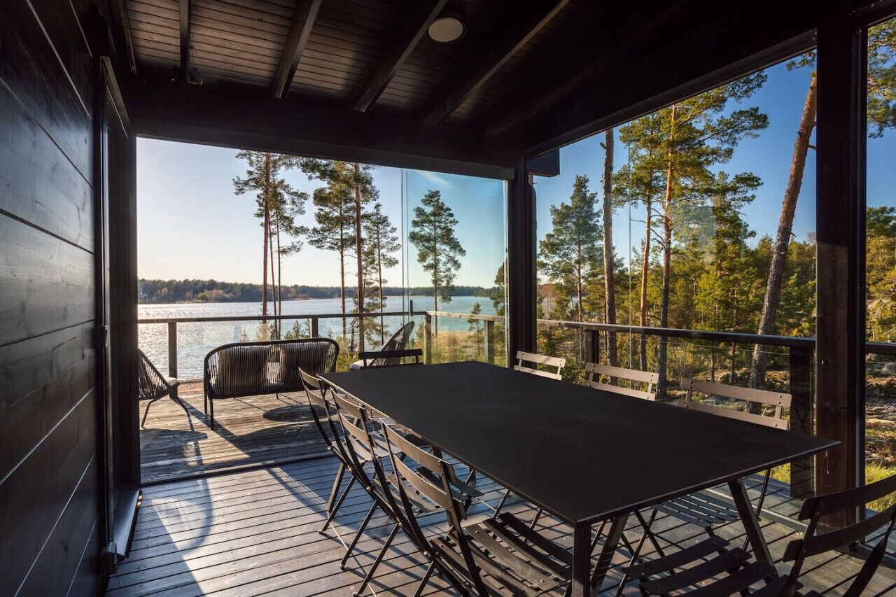 Puinen terassi, jossa on pöytä ja tuoleja, ja josta avautuu näkymä järvelle ja metsään.