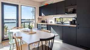 Une cuisine moderne dotée de grandes fenêtres, un coin repas avec une table et des chaises, et une vue sur un lac.