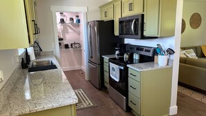 A compact kitchen with a refrigerator, microwave, stove, and granite countertop. - NEW Bungalow - Fenced yard - 30+ day rental - View of Lookout Mountain - Chattanooga (Chattanooga)