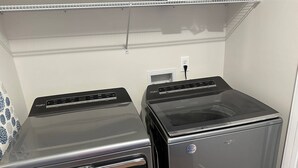 Two stacked Whirlpool washing machines in a laundry room with a white wall and a power outlet. - NEW Bungalow - Fenced yard - 30+ day rental - View of Lookout Mountain - Chattanooga (Chattanooga)
