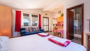 Quarto de hotel com cama, sofá, área de refeições e banheiro.
