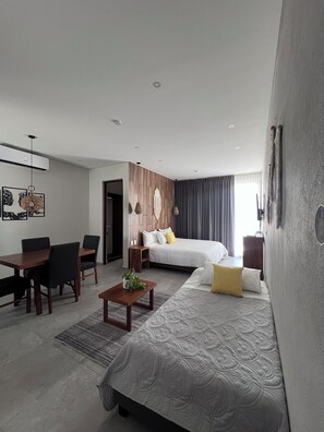 Relax in a spacious room with a large bed, seating area, and air conditioning for a comfortable stay.