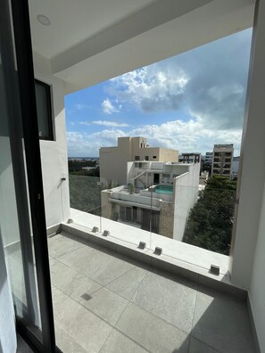 Enjoy a clear view of the surrounding urban landscape from this balcony with a glass railing and tiled floor.