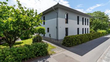 A modern two-story building with a flat roof, rectangular windows, and a paved driveway.