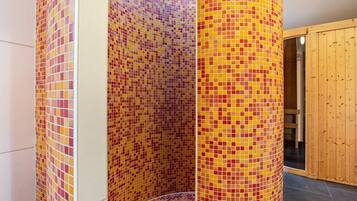 A bathroom with mosaic tile walls, a wooden door, and a tiled floor.