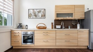 A modern kitchen with wooden cabinets, a built-in oven, and a window with blinds.