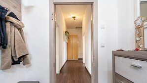 A hallway with a bench, a coat rack, a wooden door, and a dresser with drawers.