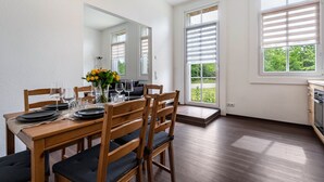 A dining area with a wooden table set for four, chairs, and a vase of flowers.