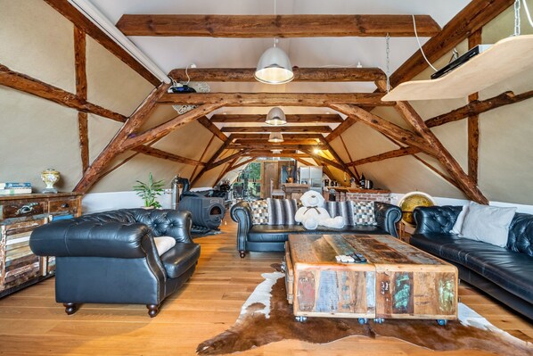 Un loft spacieux avec des poutres apparentes, des canapés en cuir, une table basse rustique et un tapis en peau de vache.