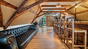 Habitación tipo loft con vigas de madera a la vista, un sofá de cuero y bancos de madera.