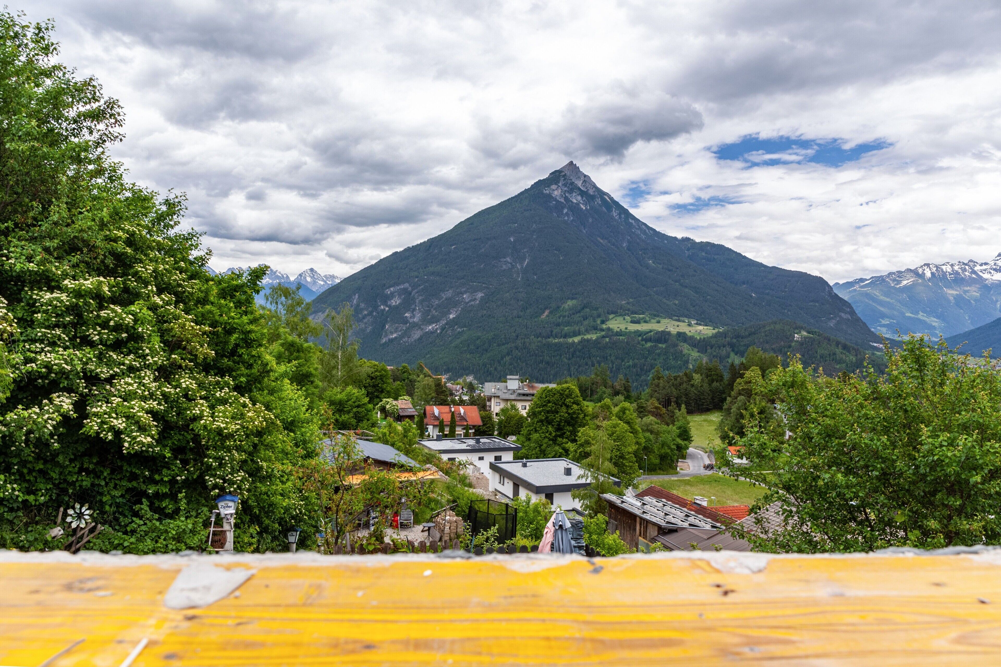 A mountain village with houses, a prominent mountain peak, and lush greenery.