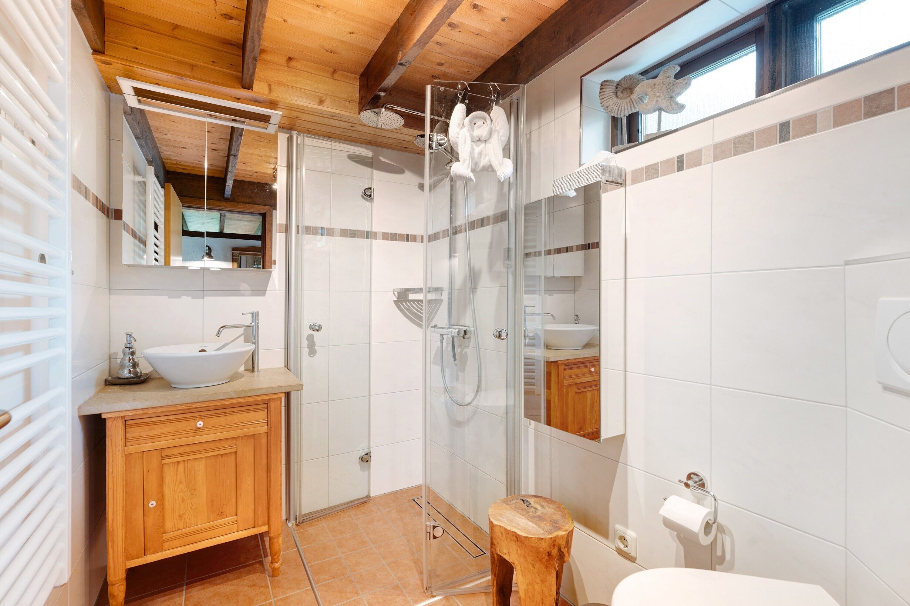 Un baño moderno con tocador de madera, cabina de ducha con mampara de vidrio y un espejo grande.