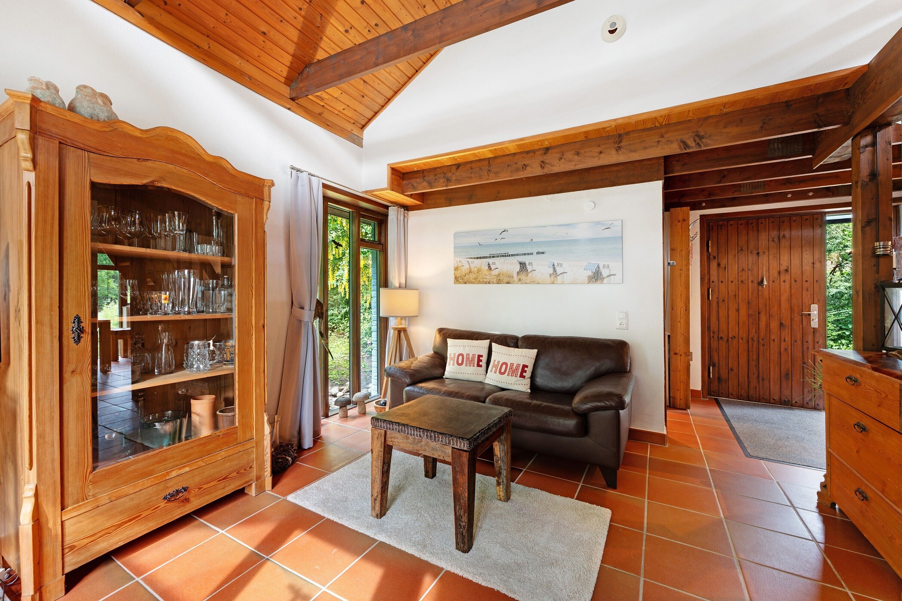 A living room with a wooden cabinet, a leather sofa, and a tiled floor.
