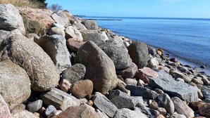 Eine felsige Küste mit großen Felsen und freiem Blick auf das Wasser.