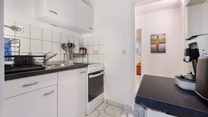 Une cuisine moderne avec des meubles blancs, une cuisinière et une machine à café.