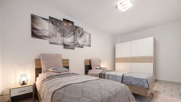 Une chambre moderne avec deux lits, une table de chevet, une armoire et des œuvres d’art murales.