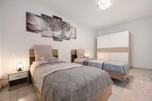 A modern bedroom with two beds, a nightstand, a wardrobe, and wall art. - Apartment 'Veith' with Wi-Fi (Hildesheim)