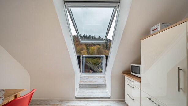 A room with a skylight, a wooden table, a red chair, and a white cabinet. - Apartment 'Burgblick' with Mountain View, Shared Garden and Wi-Fi (Hausach)