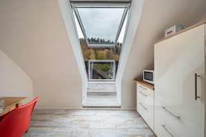 A room with a skylight, a wooden table, a red chair, and a white cabinet. - Apartment 'Burgblick' with Mountain View, Shared Garden and Wi-Fi (Hausach)
