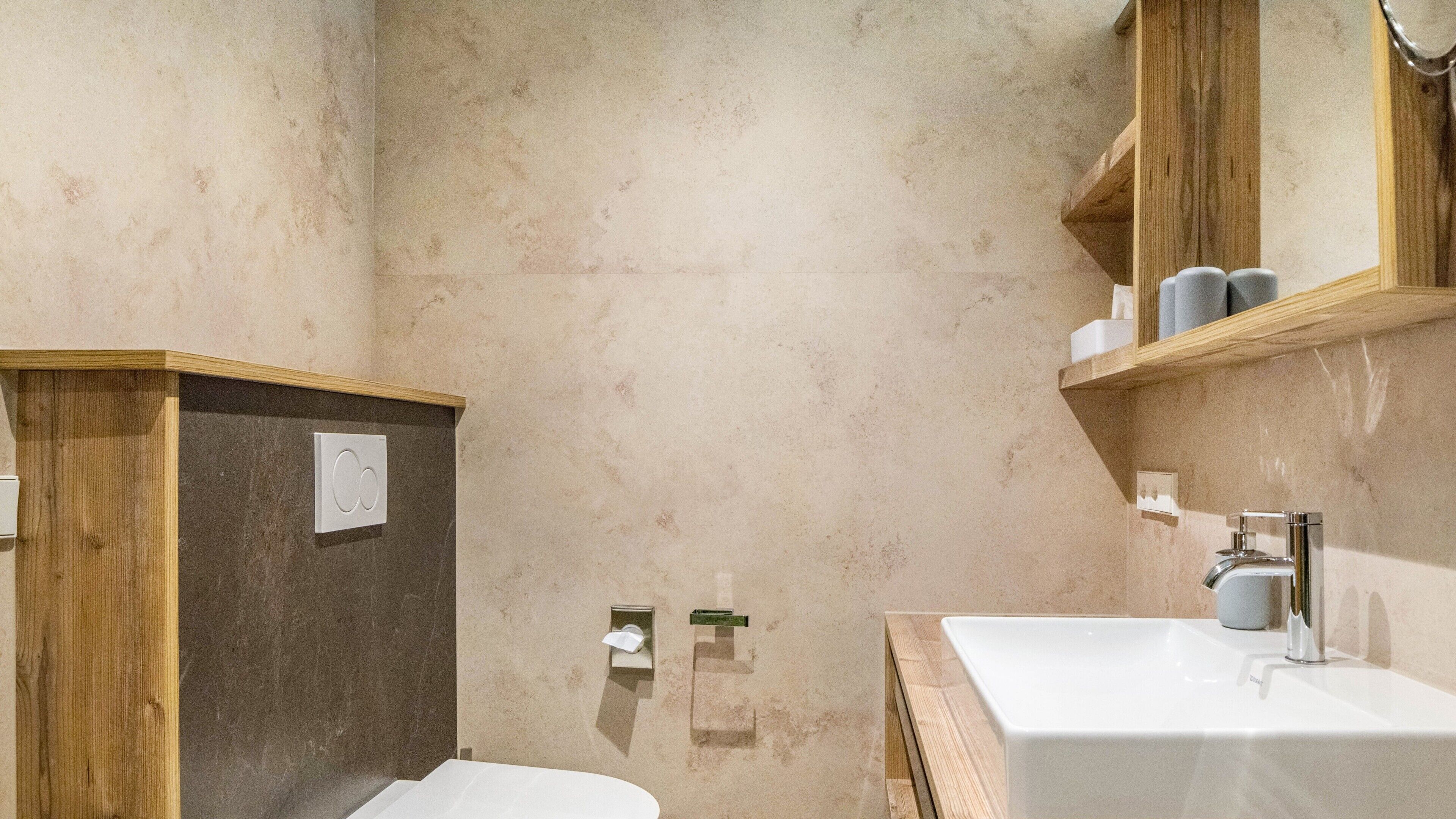 Ein Badezimmer mit einem Holzkosmetikschrank, einem weißen Waschbecken und einer Duschkabine.