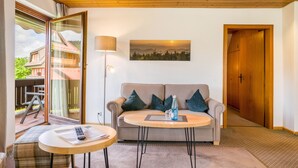 Une pièce comprenant un canapé, une petite table ronde, une lampe et un tableau accroché au mur.