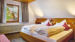 Une chambre avec un grand lit, une fenêtre avec des rideaux, un radiateur et un plafond en bois.