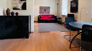 Una sala de estar moderna con un sofá rojo, un tapete a rayas negras y blancas, y un comedor con una mesa y sillas.