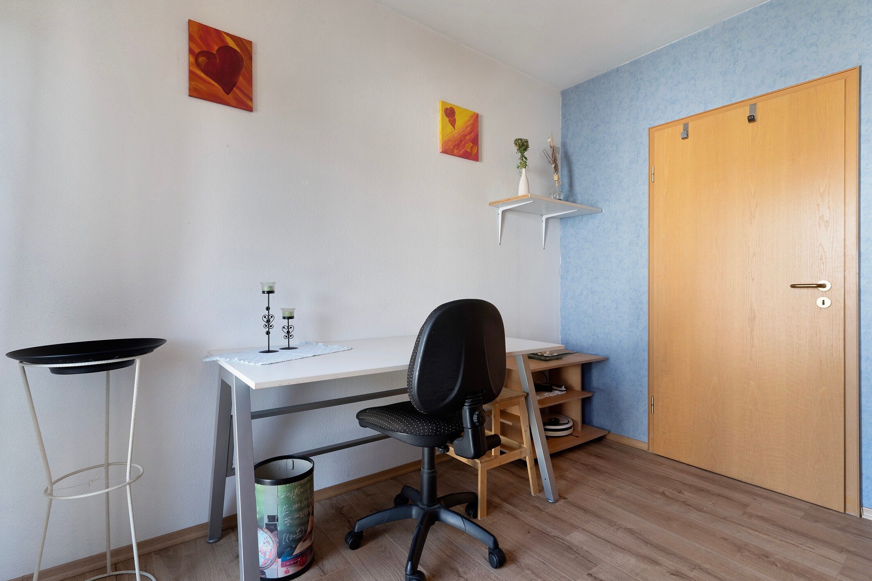 Una habitación con escritorio, silla y puerta.