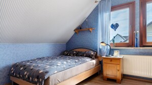 A bedroom with a bed, a nightstand, a window with curtains, and a radiator. - Holiday Home 'Ferienhaus Am Rhein' with Private Terrace, Balcony and Wi-Fi (Rheinau)