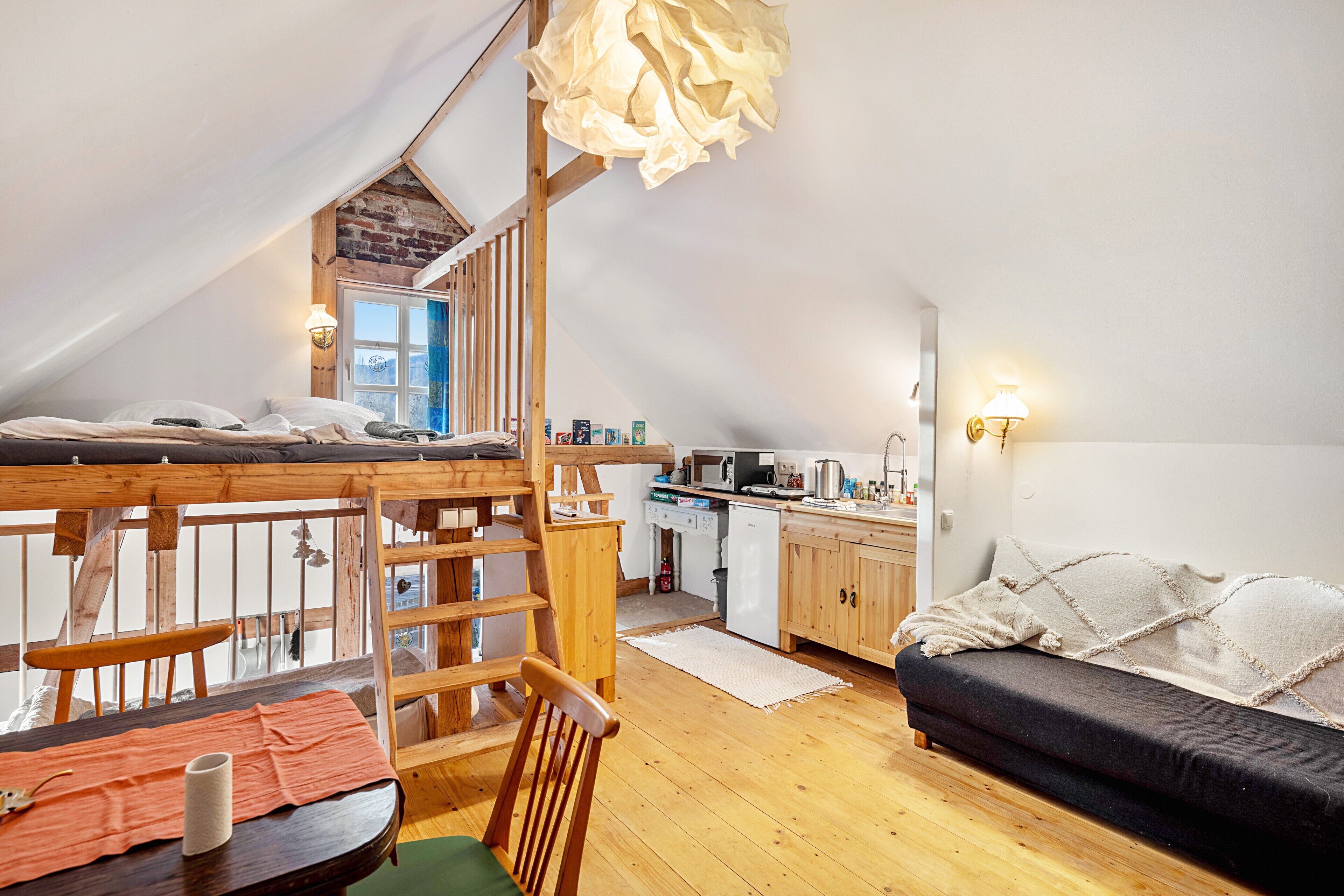 Un dormitorio tipo loft con literas, muebles de madera, una kitchenette y vistas al exterior.
