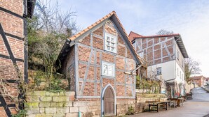 Un edificio tradicional con entramado de madera, un muro de piedra, una puerta de madera y un banco en el exterior.
