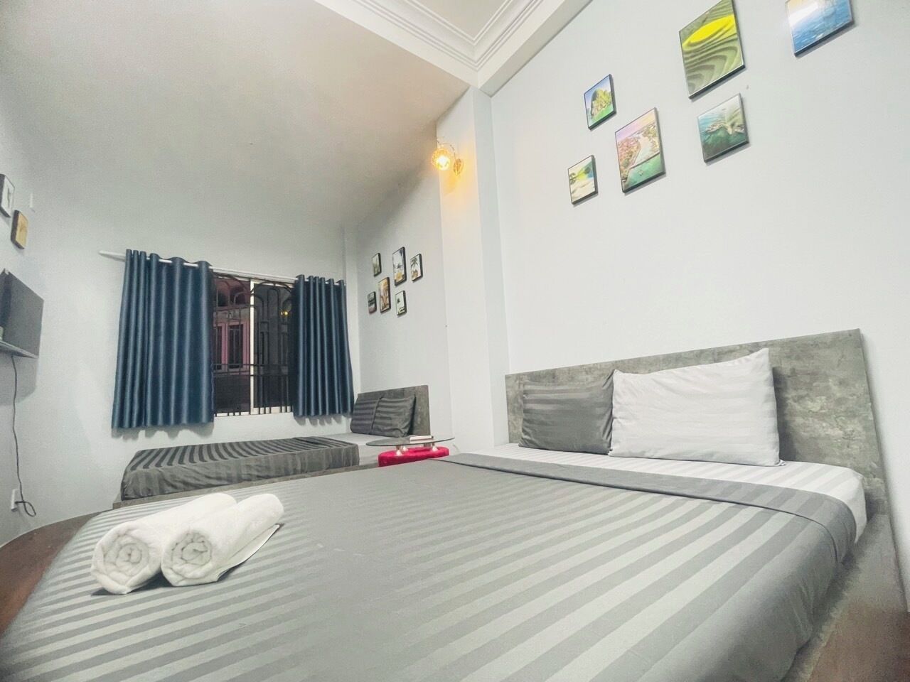 A hotel room with a large bed, a sofa, a TV, and a window with curtains.