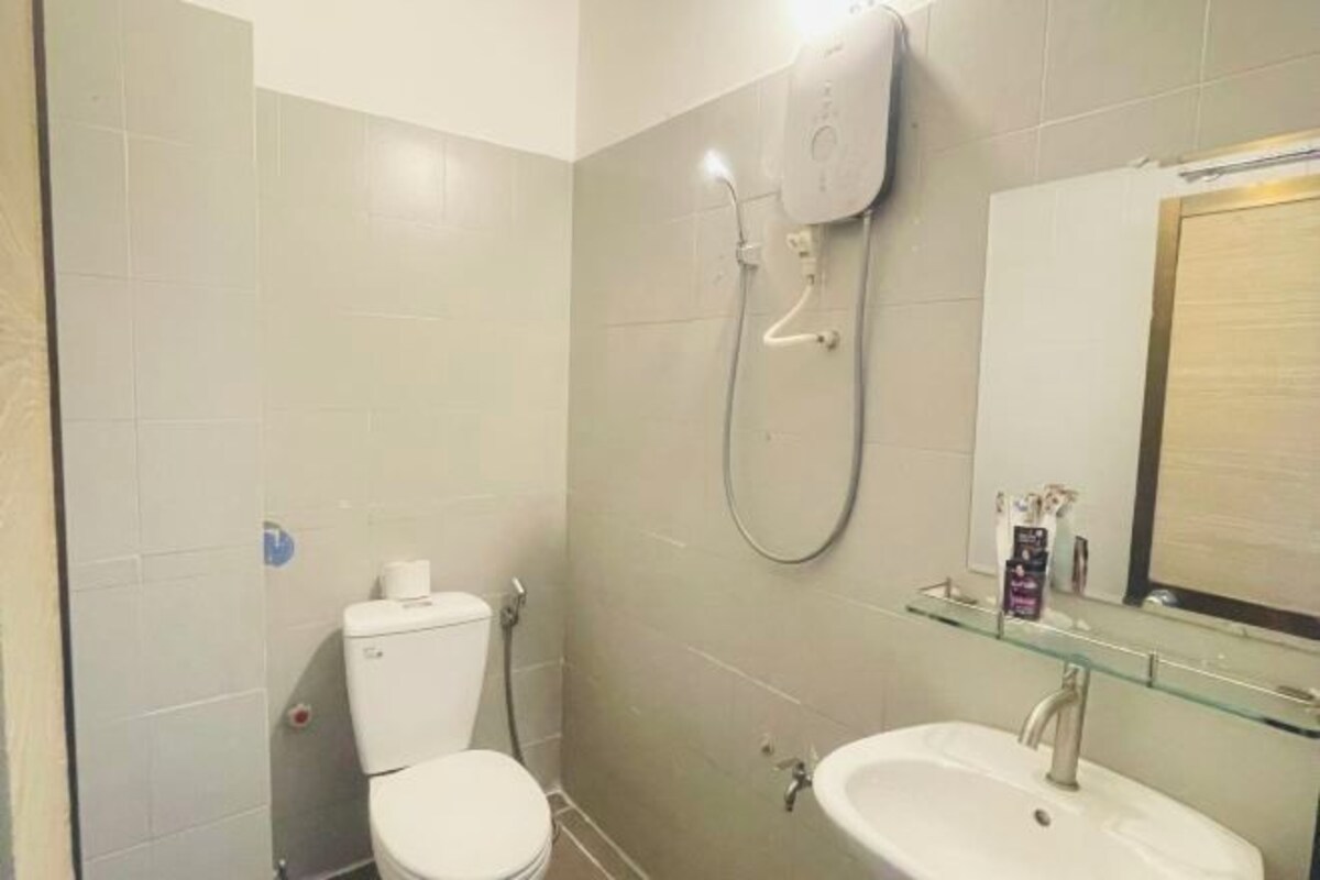A bathroom with a toilet, a glass shower enclosure, and a sink with a mirror above it.