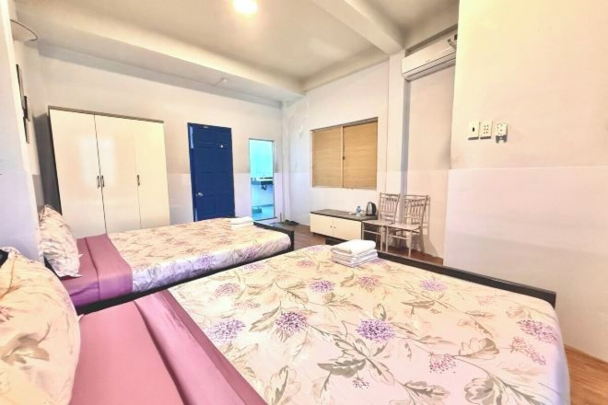 Quarto com duas camas, uma escrivaninha, uma cadeira e um guarda-roupa.