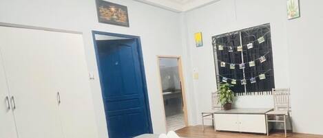 Una habitación con cama, escritorio, silla, armario y aire acondicionado.