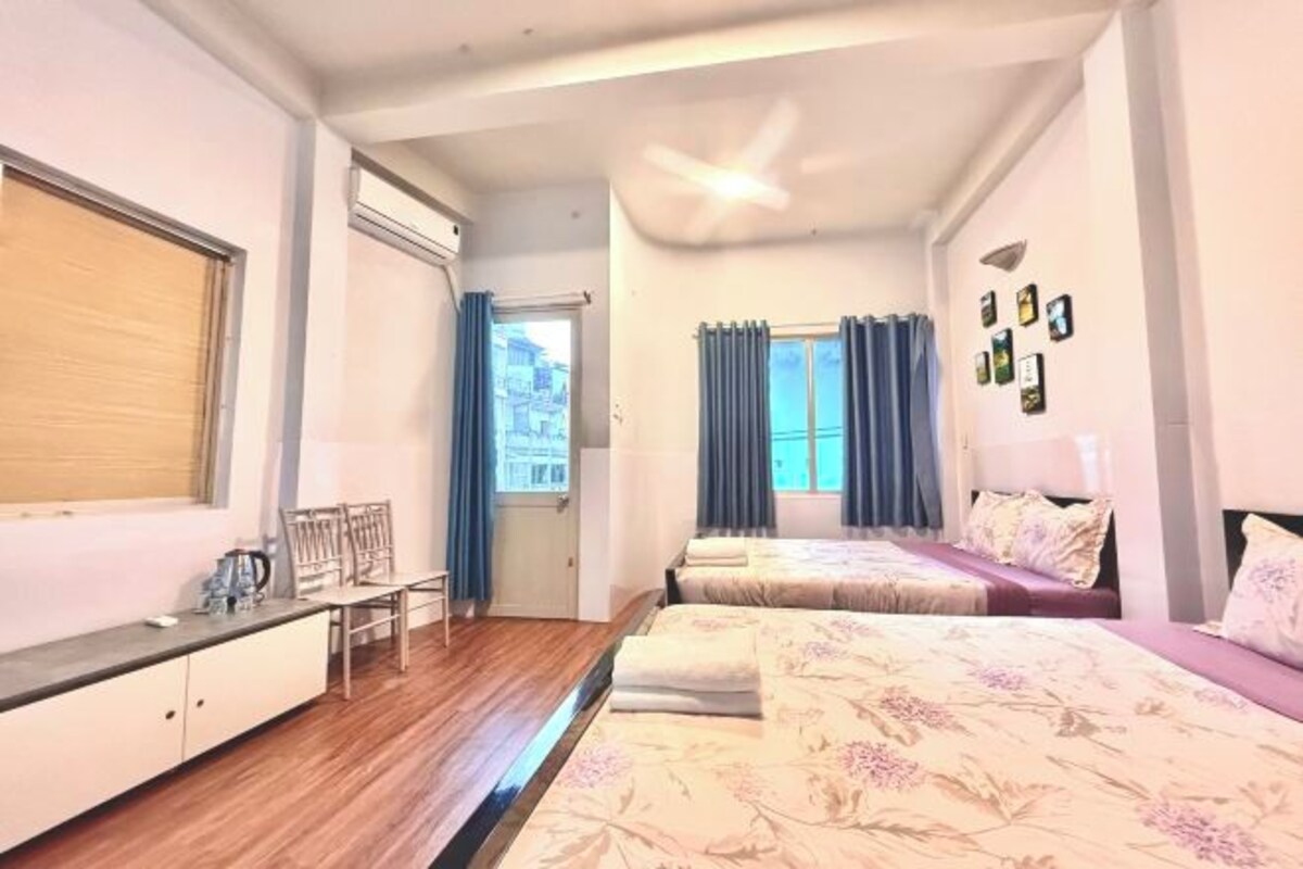 A bedroom with two beds, a desk, and a chair.