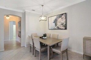 Un coin repas avec une table et des chaises en bois, un luminaire suspendu et un tableau encadré au mur.