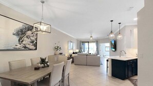 A spacious living area with a dining table, sofa, and kitchen area.