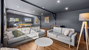 A modern living room with two grey sofas, a round coffee table, and a wooden floor. - The Absolute Beach Escape For 21 (St Leonards)