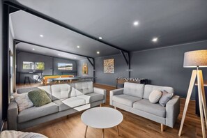A modern living room with two grey sofas, a white coffee table, and a wooden floor.