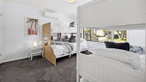 A modern bedroom with bunk beds, a small desk, and a window with a view of the outdoors. - The Absolute Beach Escape For 21 (St Leonards)