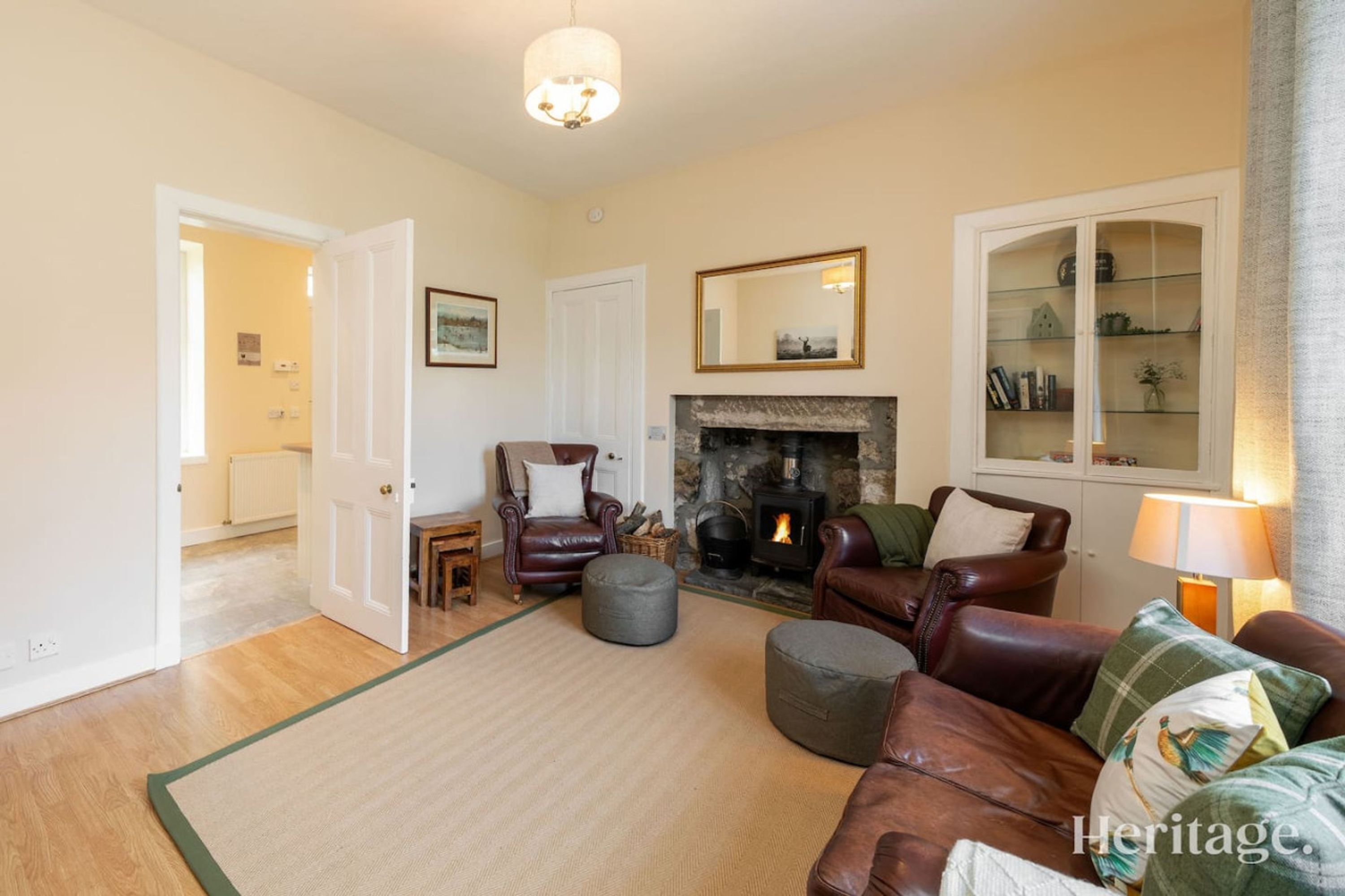 A cozy living room with a fireplace, leather sofas, and a large mirror.