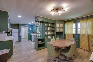 A spacious kitchen with a dining area, wooden flooring, and green cabinetry.